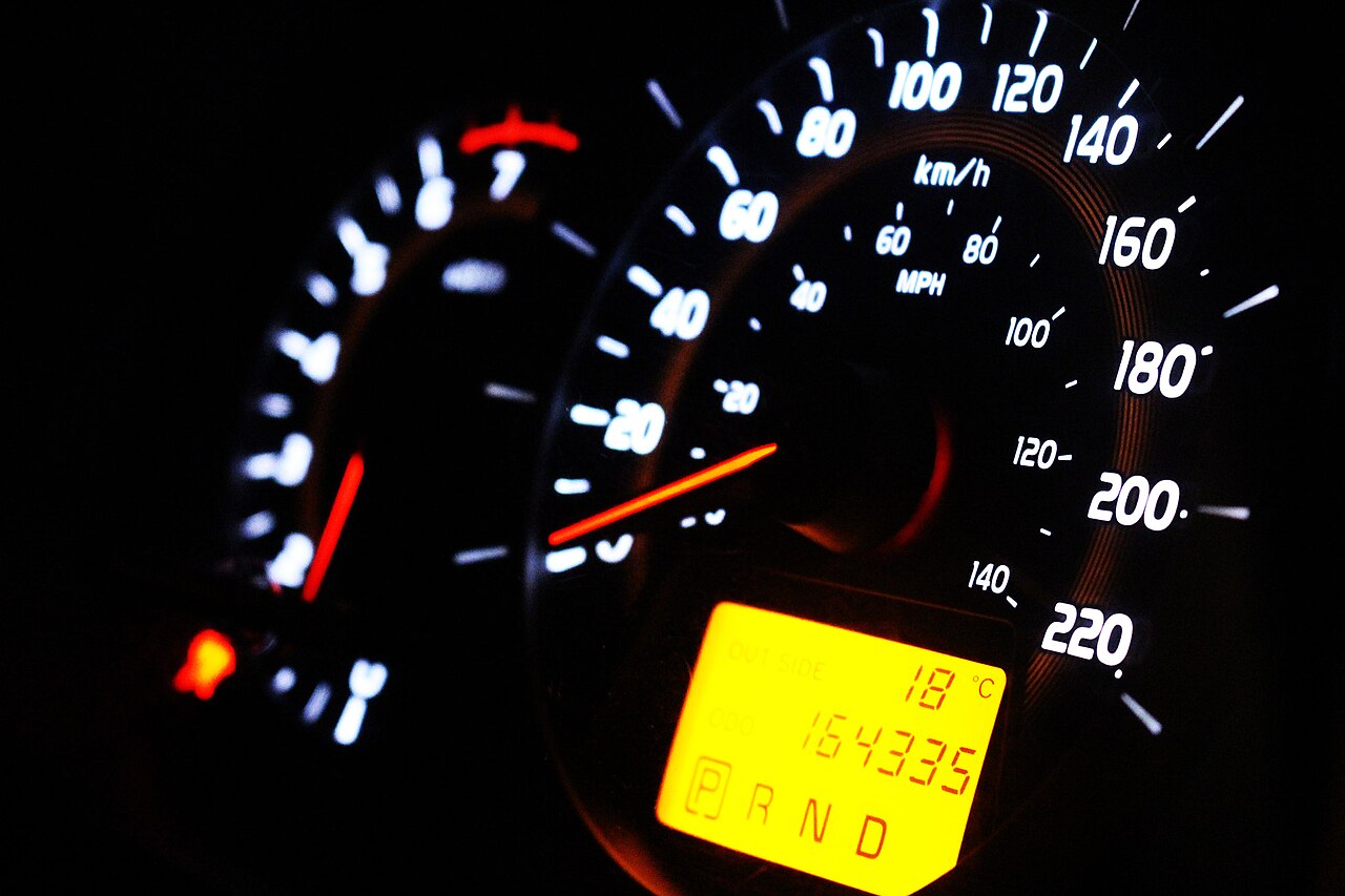 A modern car speedometer glowing at night