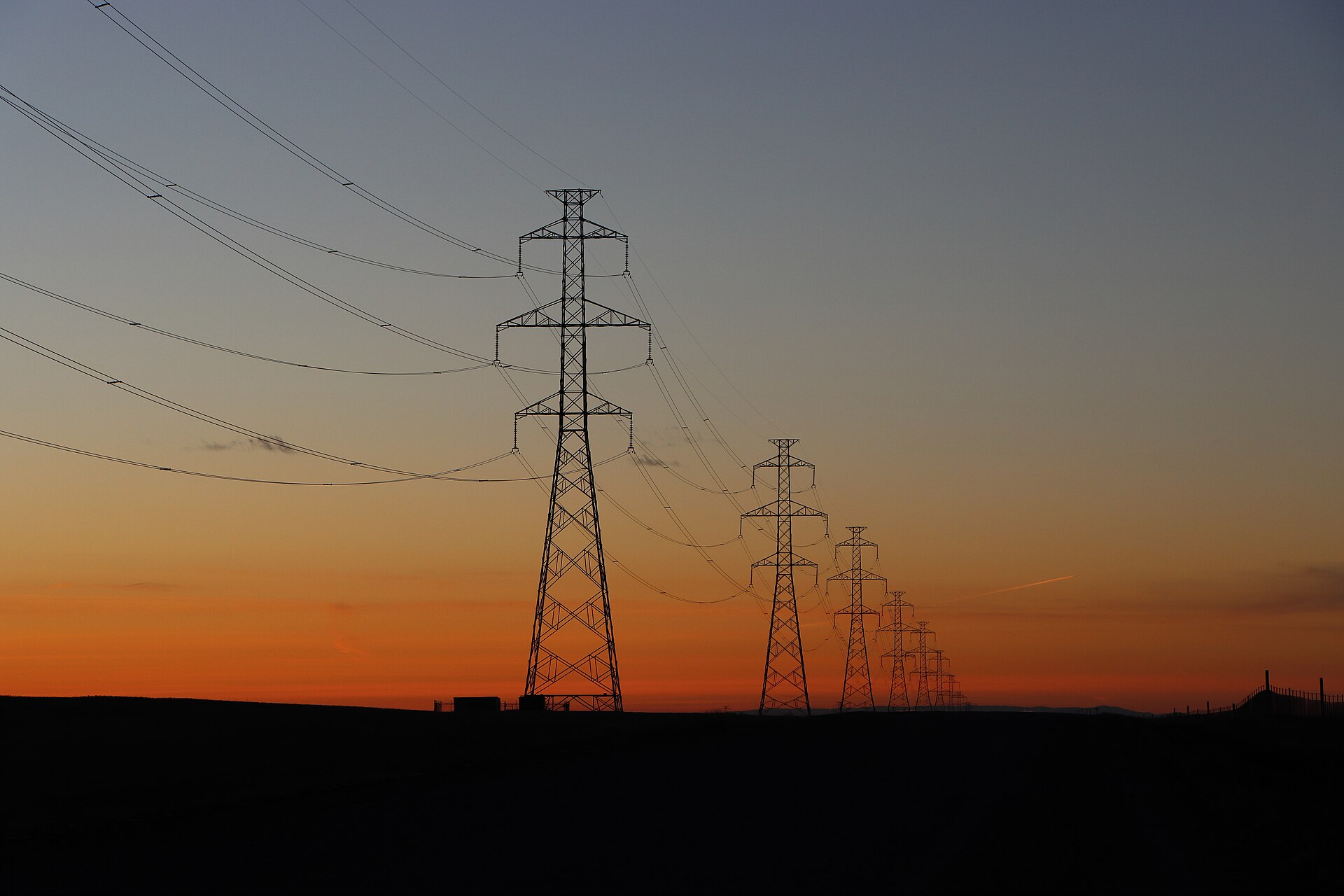 High-voltage transmission lines silhouetted at sunset